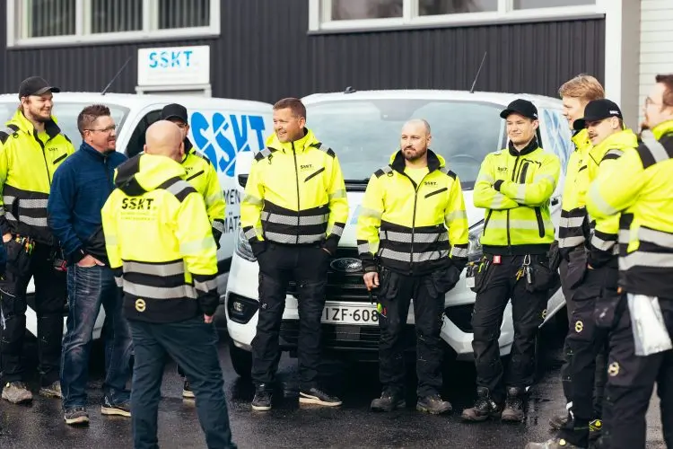 SSKT henkilöstöä SSKT:n huoltoautojen edessä